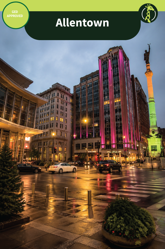 Center Square in Allentown, Pennsylvania at dusk after rain, with an art-deco tower lit in magenta and a tall stone monument column beside wet brick paving.