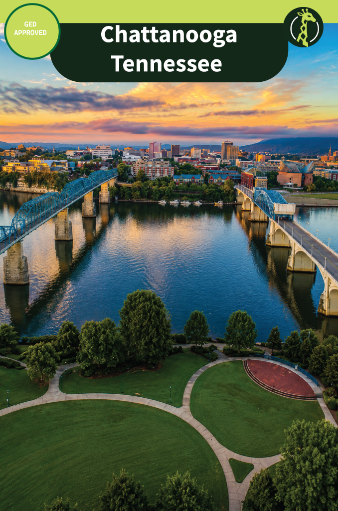 Chattanooga, Tennessee at sunset from the air, with a blue truss bridge and a second bridge crossing the Tennessee River toward the downtown skyline, and a riverside park below.