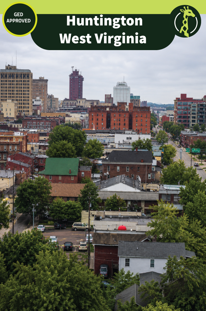 Downtown Huntington, West Virginia seen from a hillside, with mid-rise office buildings above brick streets and green trees filling the foreground.