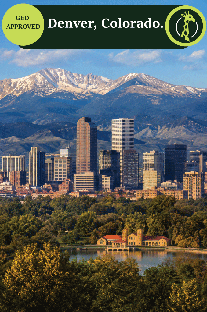 The Denver skyline at dusk with the Rocky Mountains behind it.